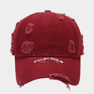 Detailed close-up of vintage distressed wine red baseball cap with embroidered brim letters