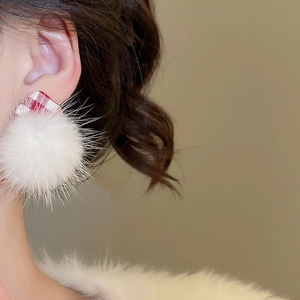 Detail view of the white plush pom-pom and red checkered fabric earring on model