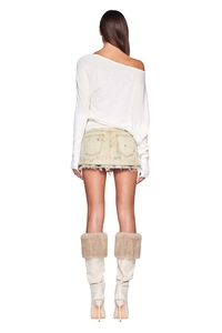Back view of a white one-shoulder knitted sweater paired with a yellow denim mini skirt