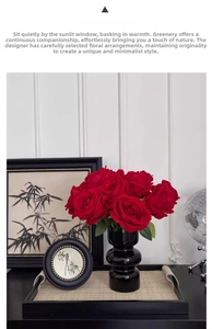 Artistic black ringed ceramic vase with deep red faux velvet roses on a black tray