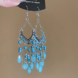Detail of silver floral tassel earrings with blue beads and water drop pendants