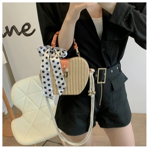Detail of heart-shaped straw bag with orange handle and polka dot scarf accessory