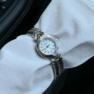 Close-up of a silver watch with mother-of-pearl dial and textured wavy metal strap