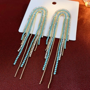 Detailed view of gold tassel earrings with turquoise beads and sparkling white crystals
