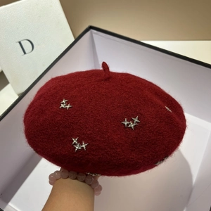 Detail of wine red wool beret featuring sparkling rhinestone stars and top stem design