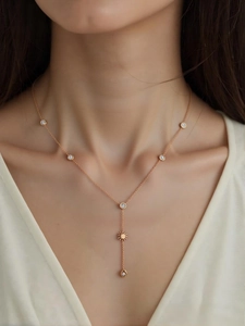 Détail d'un collier en Y or rose avec pendentif soleil et zircons porté par un mannequin