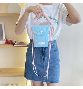 Close-up of light blue nylon phone bag with pink padded handle and drawstring strap