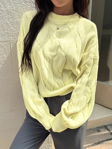 Detailed view of pale yellow knit sweater featuring diamond cable pattern and round neck