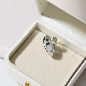 Adjustable silver ring featuring engraved black daisy flower in a white jewelry gift box