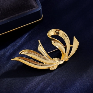 Elegant gold-tone abstract ribbon brooch with brushed texture on blue silk background