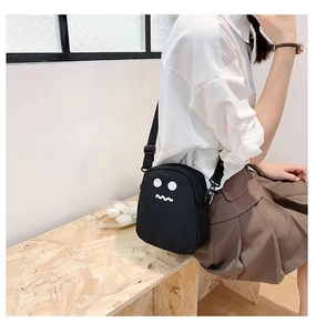Photo lifestyle d'un sac bandoulière noir avec un motif de vagues et d'yeux mignons