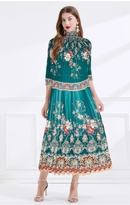 Detail of green floral pleated maxi dress featuring bohemian prints and a high neck