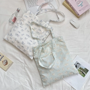 Detail shot of cute cat print canvas tote bags on a bed with lifestyle accessories