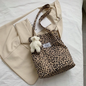 Detail of leopard print canvas tote bag featuring a cute bear pendant and metal clasp
