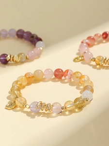 Detail of beaded bracelets with amethyst, citrine, and golden snake charms