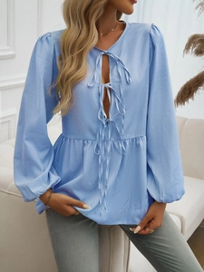 Detailed view of striped blouse with lantern sleeves and front tie bow closures