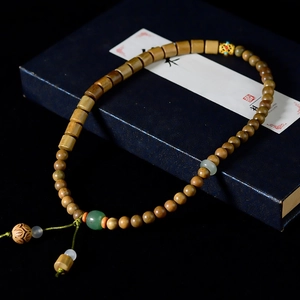 Detail of sandalwood bead bracelet with green jade and carved lotus on dark gift box