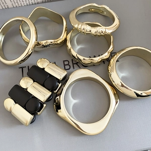 Détail d'un ensemble de 7 bracelets joncs géométriques dorés et noirs au style chic