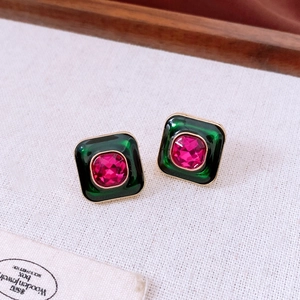 Close-up of vintage square earrings with pink cushion-cut stone and green enamel