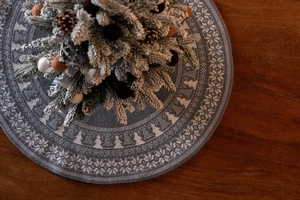 Detail of blue-grey knitted Christmas tree skirt with forest snowflake pattern on wood