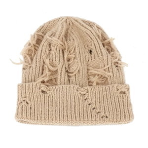Detailed macro view of beige knitted hat featuring heavy distressed holes and long tassels