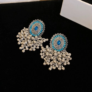 Detailed macro of vintage ethnic earrings with blue gemstones and metallic beaded fringe