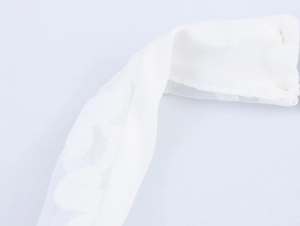 Detailed close-up of white lace fabric with intricate floral embroidery and sheer tulle