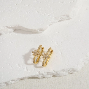 Detailed macro view of gold-plated oval hoop earrings with sparkling zircon snowflake charms