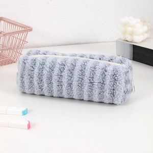 Close-up of soft blue plush pencil case with white zipper on a clean desktop