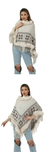 Detail of beige knit poncho featuring snowflake patterns, faux fur collar and fringe hem