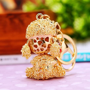 Close-up of a golden metal poodle keychain with hollow heart design and rhinestone texture