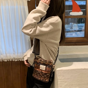 Detail view of plush textured crossbody bag with knitted floral pattern and woven strap