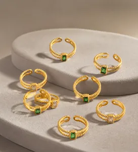 Detail of adjustable gold ring set with emerald cut green stones and twisted texture