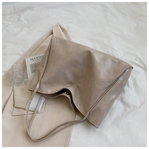 Detailed close-up of a large soft leather tote bag on bedding with a lifestyle aesthetic
