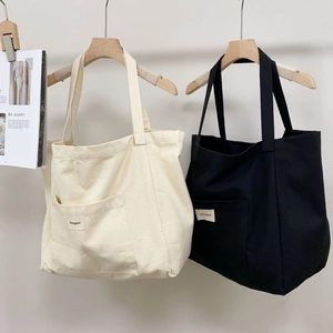 Detailed close-up of minimalist black and beige canvas tote bags with front pockets