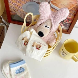 Gros plan de chaussettes en coton avec motifs de chien et pois roses dans un décor doux