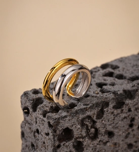 Detail of minimalist dual-layer S925 silver ear cuffs in gold and silver on volcanic rock