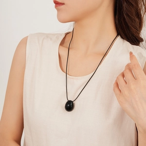 Détail du pendentif ovale noir en pierre sur un collier en cordon ciré fin pour femmes