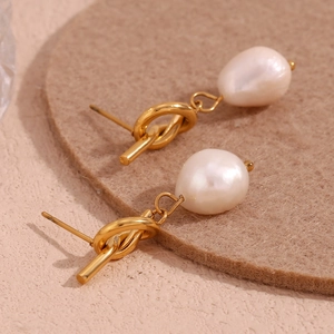 Detailed close-up of 18K gold-plated knotted stud earrings with baroque freshwater pearls