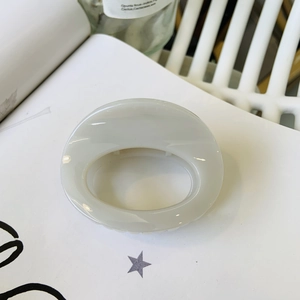 Detail of light gray oval hair claw clip with smooth finish on minimalist white background