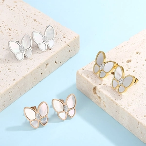Detailed view of butterfly earrings in gold and silver with white mother of pearl inlay