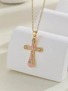 Macro view of gold cross necklace with pink enamel and white sparkling zircons