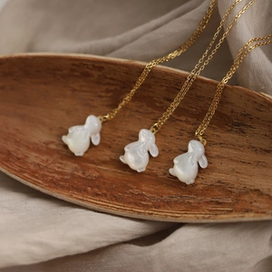 Détails des pendentifs lapin en nacre blanche sur une chaîne de collier en acier doré