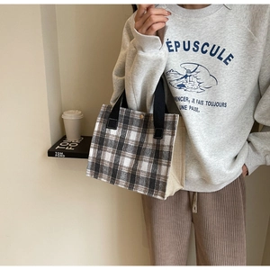 Detail view of a compact brown and black checkered canvas tote bag with black handles