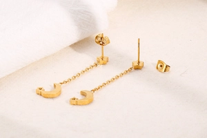 Detail view of gold star and moon drop earrings crafted in polished stainless steel