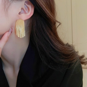 Elegant gold fringe fan-shaped tassel earrings with smooth metallic finish on model