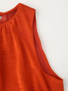 Detail shot of orange-red satin sleeveless dress neckline with a silver button accent