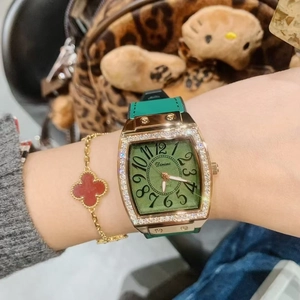 Close-up of a green square face watch with gold diamond bezel on a woman's wrist