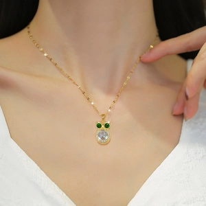 Luxurious gold owl necklace with green gemstone eyes and clear crystal pendant on a model
