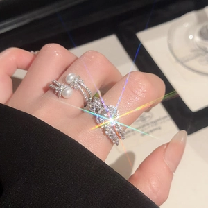Detailed view of silver bow ring with shimmering cubic zirconia and white pearls